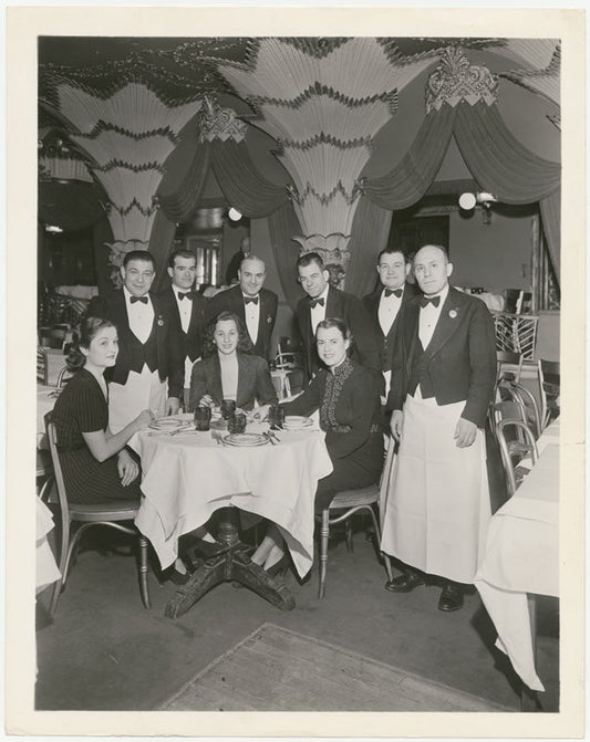 Unidentified diners and array of waiters around table at the nightclub Billy Rose's Diamond Horseshoe