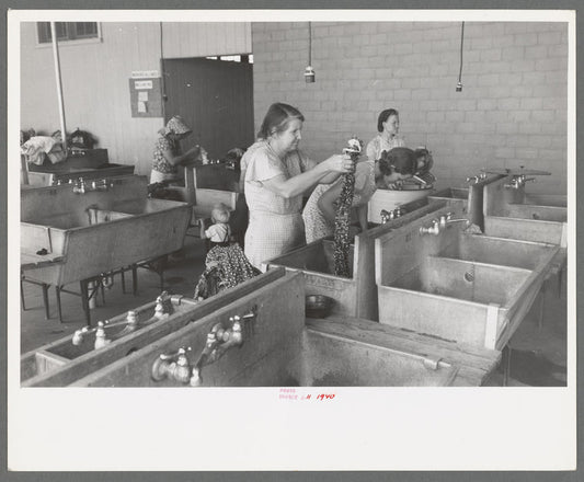 Wives of migratory workers in the laundry room at the Agua Fria Migratory Labor Camp, Arizona. Hot and cold water are furnished by the camp, soap and other washing materials by the people