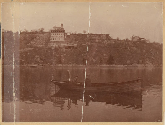 Two men in small boat; view of Fort Wendel amusement park
