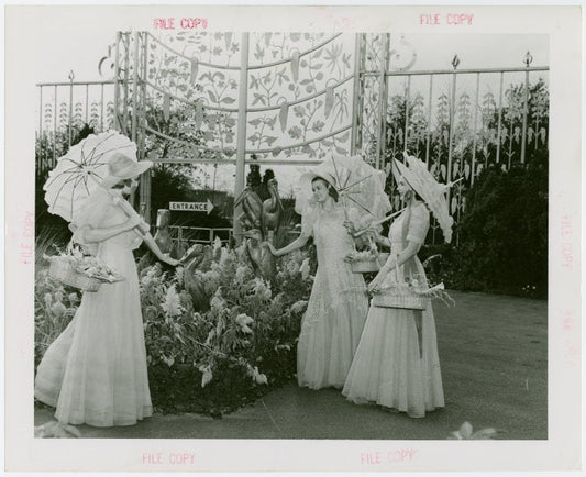 Gardens on Parade - Three women with parasols and baskets examining sculpture